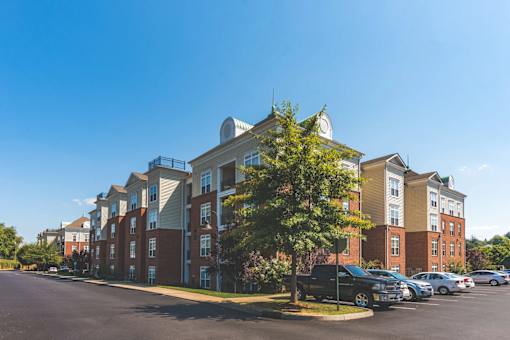 A large apartment complex with a parking lot in front.