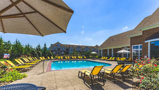 A pool surrounded by yellow chairs and umbrellas.