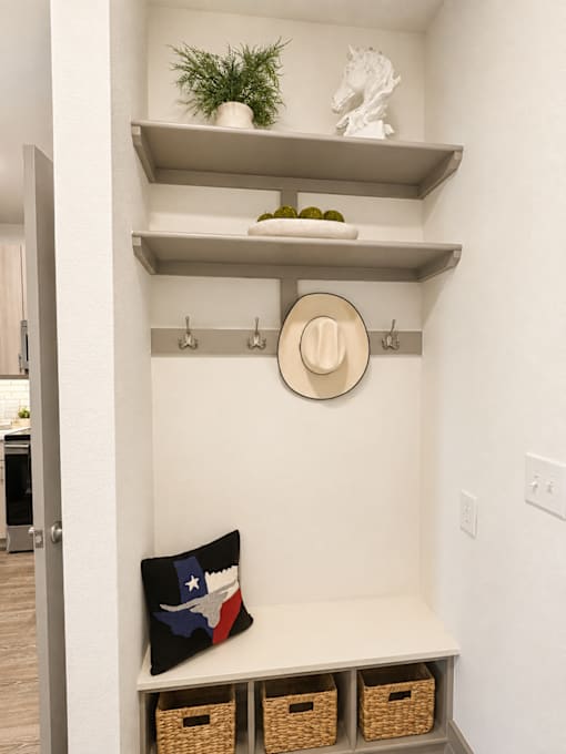 A white wall with a shelf and a pillow with a Texas flag on it.