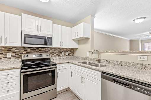 A kitchen with white cabinets and a black stove top oven.
