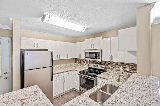 A kitchen with a refrigerator, oven, and microwave.