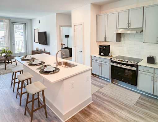 A kitchen with white cabinets and a white island with a sink.