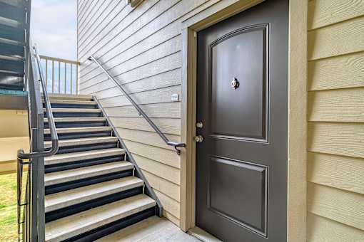 A grey door is on the right side of a staircase.