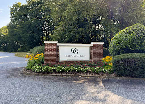 A sign that says "Georgia Green" is surrounded by flowers and greenery.