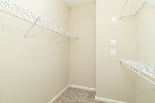 A small, empty room with a carpeted floor and two shelves.