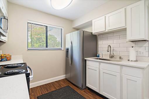 A kitchen with a stainless steel refrigerator and white cabinets.