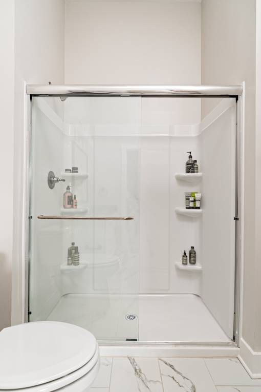 A white toilet sits in a glass shower stall.