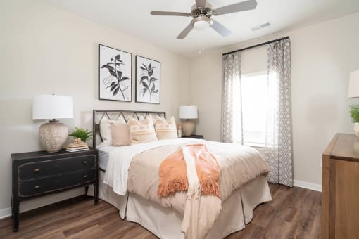 Dog-Friendly Luxury Apartments in Alcoa, TN - Vintage Hunters Crossing - Bedroom with a Bed, Hardwood-Inspired Flooring, Nightstands, Lamps, Wall Arts, Dresser, and Ceiling Fan with Lighting.