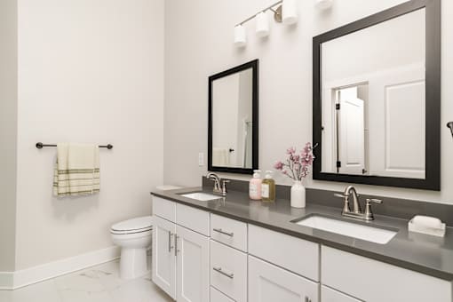 A bathroom with a toilet, sink, and mirror.