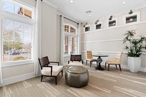 A living room with a large window, a chair, a table, and a potted plant.