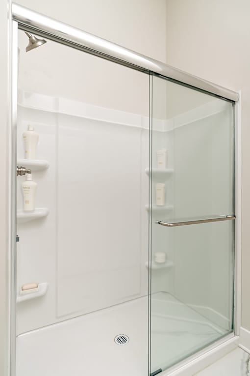 A white shower stall with a glass door and a silver handle.