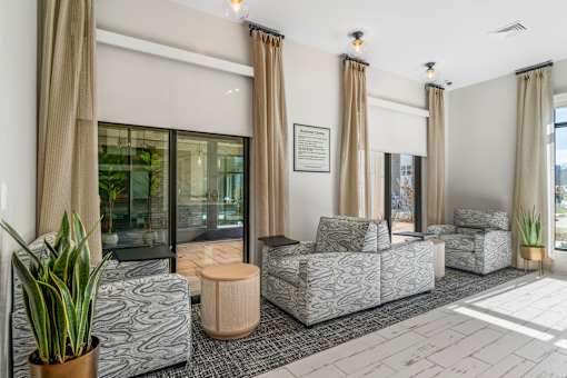 A living room with grey patterned couches and a potted plant.