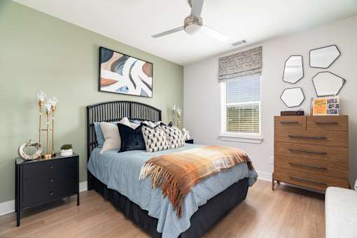 A bedroom with a bed, dresser, and ceiling fan.