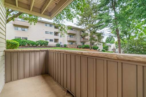A balcony with a brown railing and a view of apartment buildings.