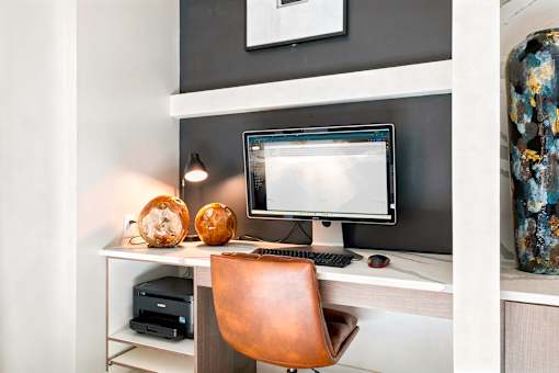 A brown leather chair sits in front of a computer monitor on a desk.