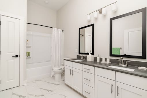 A white bathroom with a toilet, sink, and mirror.