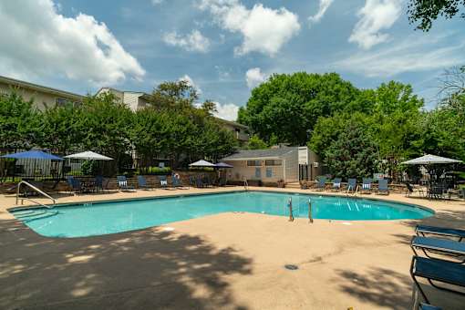 A large swimming pool surrounded by trees and a building in the background.