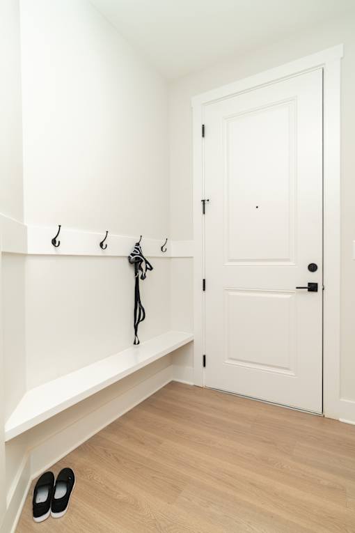 A pair of black shoes are on the floor next to a white door.