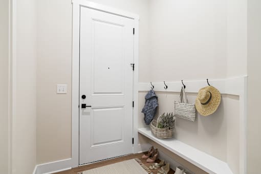 A white door is closed with a black handle and a white wall with a light switch.