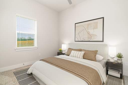 A bedroom with a large bed and a window with blinds.