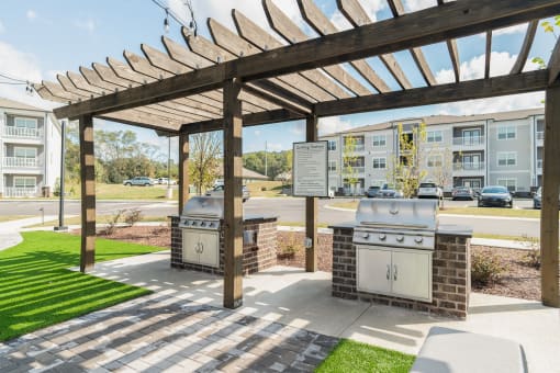 two bbq pits at the clubhouse of an apartment building with awning