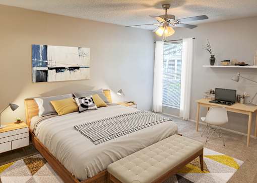 A bedroom with a bed, desk, and chair.