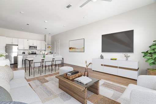 A modern living room with a white sofa, a wooden coffee table, and a flat-screen TV mounted on the wall.