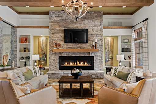 A living room with a stone fireplace and a chandelier.