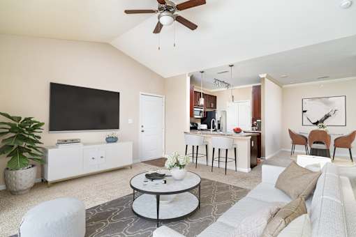 A living room with a white couch, a coffee table, and a television.