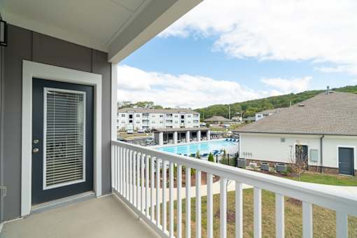 A balcony with a view of a pool and houses.