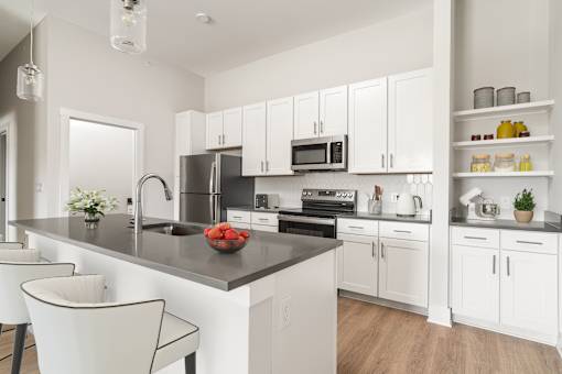 A modern kitchen with white cabinets and a black countertop.