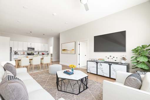 A modern living room with a white sofa, a coffee table, and a kitchen area in the background.