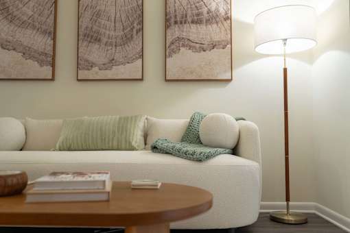 A living room with a white couch, a wooden coffee table, and two abstract paintings on the wall.