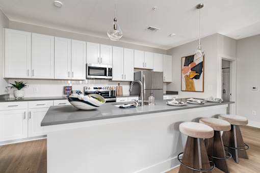 A kitchen with white cabinets and a grey countertop.