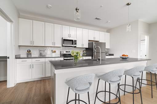 A kitchen with white cabinets and a grey island.