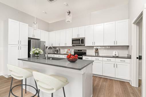 A kitchen with white cabinets and a grey island.