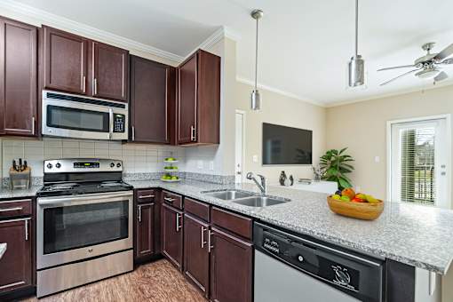 A kitchen with brown cabinets and a black dishwasher.