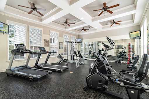 a gym with cardio machines and ceiling fans