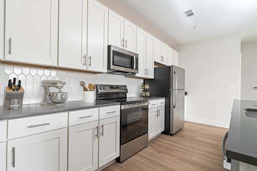 A kitchen with white cabinets and a black refrigerator.
