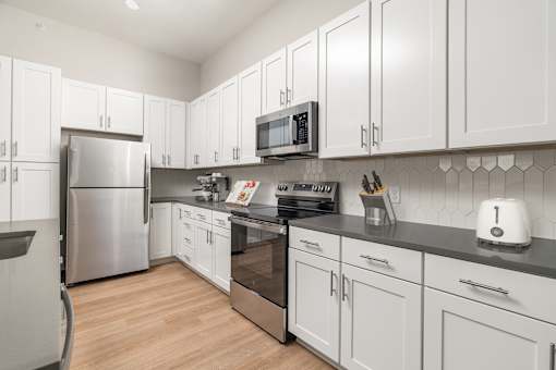 A modern kitchen with white cabinets and stainless steel appliances.