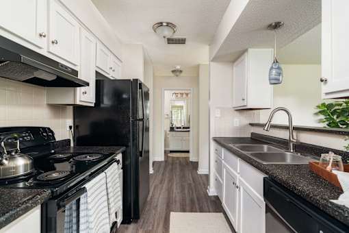 A kitchen with black appliances and white cabinets.
