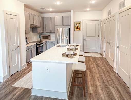 A kitchen with a white island and wooden floors.