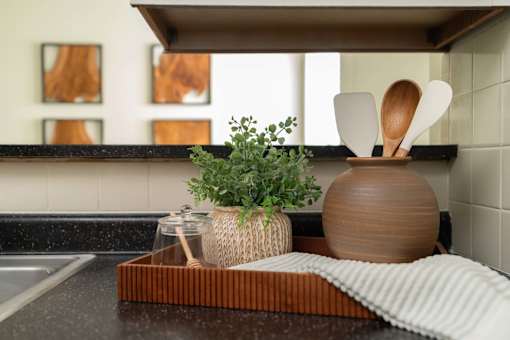 A kitchen counter with a plant, wooden utensils, and a jar.
