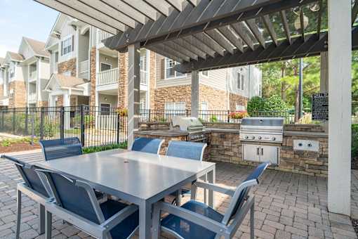 a patio with a table and chairs and a grill