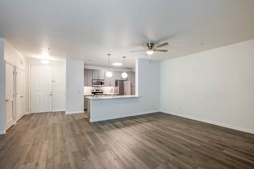 A spacious kitchen and living room with wood flooring and white walls.
