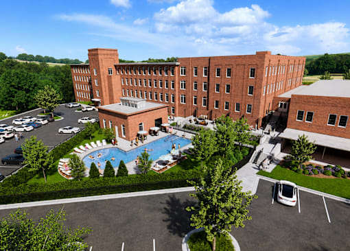 A large red brick building with a pool in the front yard.