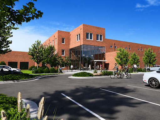 A red brick building with a glass entrance and people walking around.