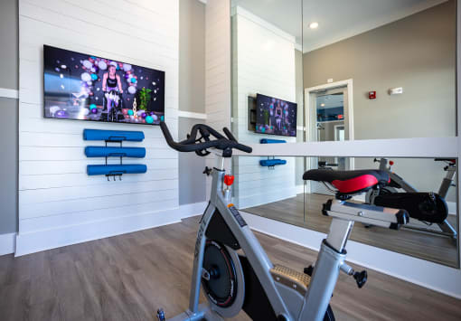 a gym with a bike and a flat screen tv