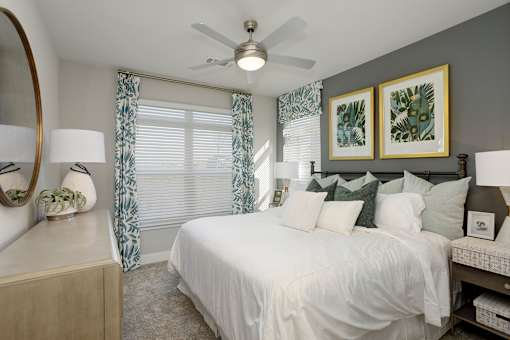 A bedroom with a white bed and green pillows.