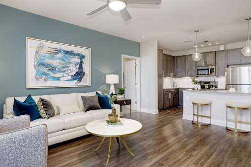 A living room with a white couch and a painting on the wall.
